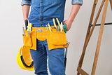 Mid section of a handyman with toolbelt and hard hat