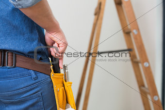 Mid section of a handyman with toolbelt