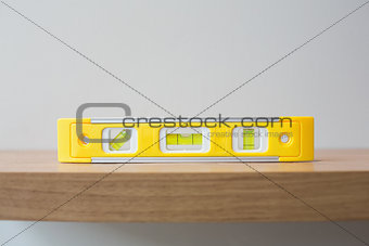 Spirit level on wooden surface against the wall
