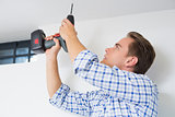 Handyman using a cordless drill to the ceiling