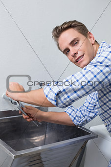 Portrait of plumber fixing water tap with pliers