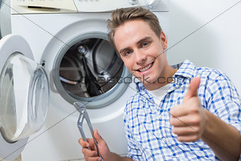 Technician repairing washing machine while gesturing thumbs up