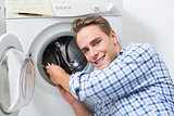 Smiling technician repairing a washing machine