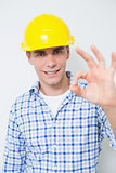 Smiling handyman in yellow hard hat gesturing okay sign