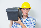 Serious handyman in yellow hard hat carrying toolbox
