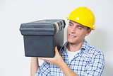 Smiling handyman in yellow hard hat carrying toolbox