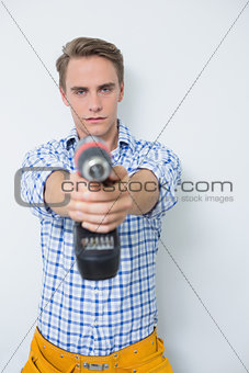 Serious handsome young handyman holding out drill