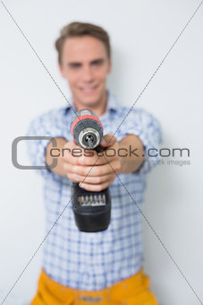Smiling handsome young handyman holding drill