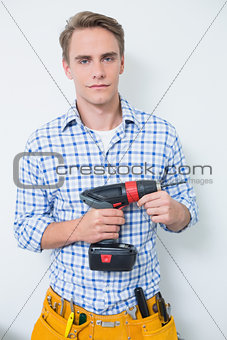 Portrait of a serious handsome young handyman holding drill