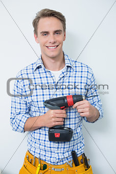 Portrait of a smiling handsome young handyman holding drill