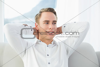 Smiling relaxed young man sitting on sofa