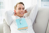 Portrait of a relaxed young man with book lying on sofa