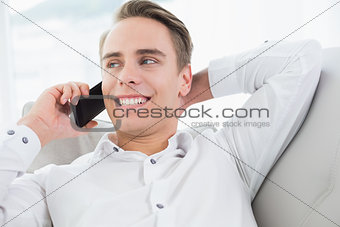 Relaxed young man using cellphone on sofa