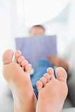 Blurred man reading a book with focus on bare feet