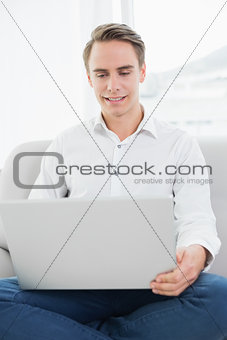 Casual young man using laptop on sofa