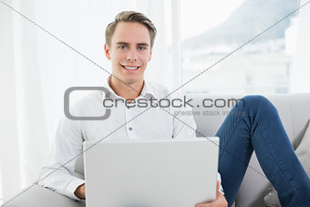 Portrait of a casual young man using laptop on sofa