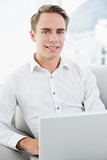 Portrait of a smiling casual young man using laptop on sofa