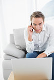 Portrait of casual man using cellphone and laptop at home