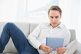 Casual young man using digital tablet on sofa