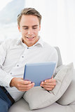 Casual young man using digital tablet on sofa