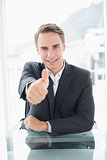 Smiling businessman gesturing thumbs up at office desk