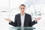 Serious businessman with hand gesture at office desk