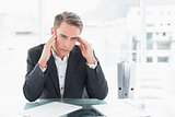 Businessman suffering from headache at office desk