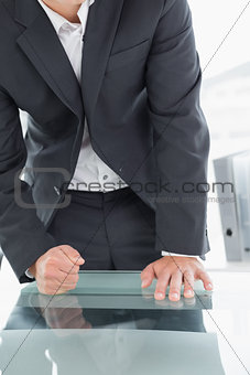 Mid section of businessman with clenched fist on office desk