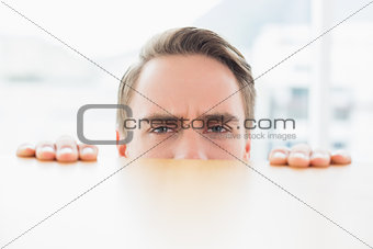 Portrait of businessman looking over blurred wall at office
