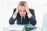 Worried businessman with head in hands at office desk