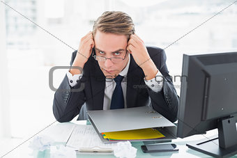 Businessman with documents and computer at office desk