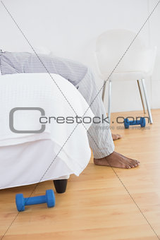 Low section of a young man in pajama lying in bed