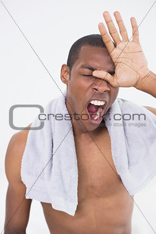 Close up of shirtless Afro man yawning with eyes closed