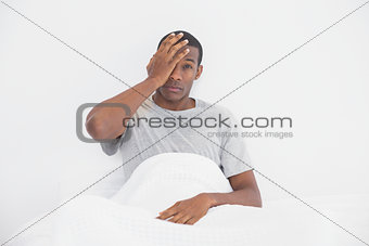 Portrait of sleepy Afro man sitting in bed