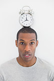 Portrait of a man with an alarm clock on top of his head