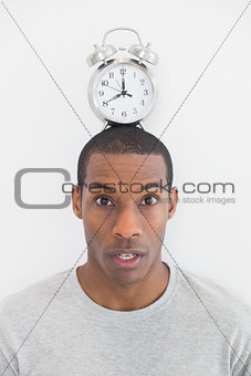 Portrait of a man with an alarm clock on top of his head