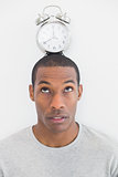 Close up of a man with an alarm clock on top of his head