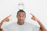 Close up of a man pointing at alarm clock over his head