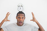 Shocked man with an alarm clock on top of his head