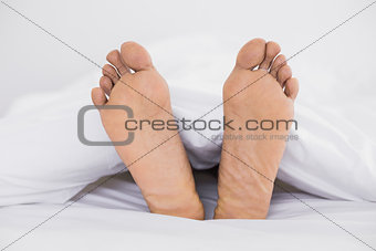 Close up of bare feet in bed