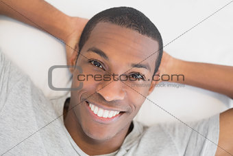 Smiling young Afro man resting in bed