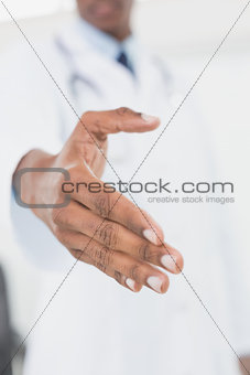 Mid section of male doctor offering a handshake