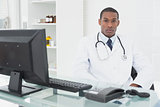 Serious male doctor with computer at medical office