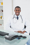 Smiling male doctor sitting with computer at medical office
