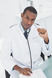 Serious doctor sitting at desk in medical office