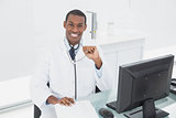 Smiling male doctor sitting with computer at medical office