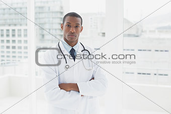 Serious doctor with arms crossed in a medical office