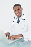 Smiling doctor using laptop at medical office