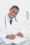 Smiling doctor writing a note at medical office