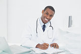 Smiling doctor writing a note at medical office